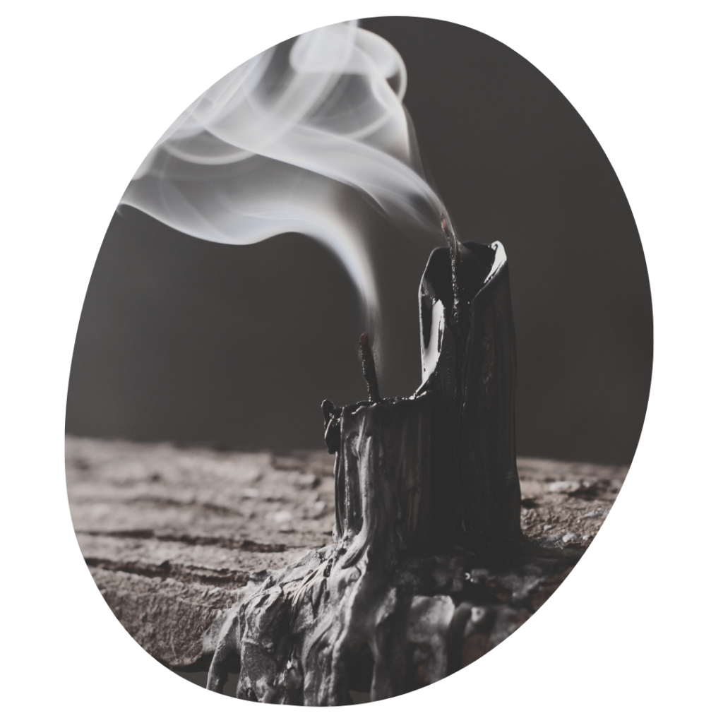 Two black taper candles that are half melted with smoking bellowing from the blown out wicks